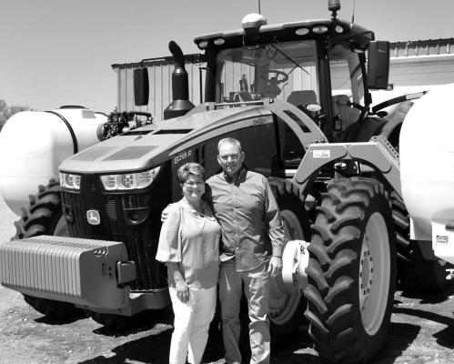 Darrin and Leah with one of the John Deere green tractors that Darrin drives through his fields.”
